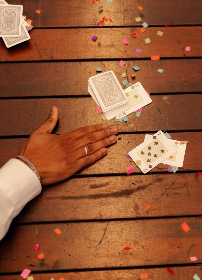 Hand sweeping cards on table with colorful confetti, symbolizing a poker win.