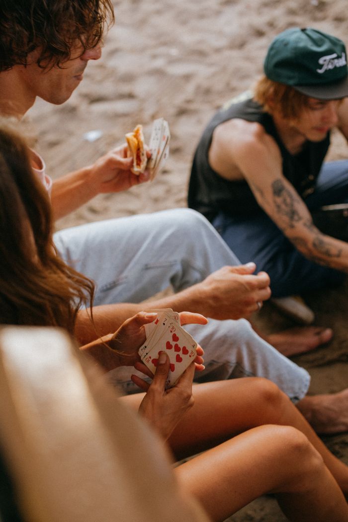 A group of friends enjoying a beach day with card games and snacks.